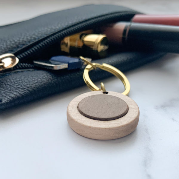 Pale white wood round key ring with walnut inlay, displayed with key in purse