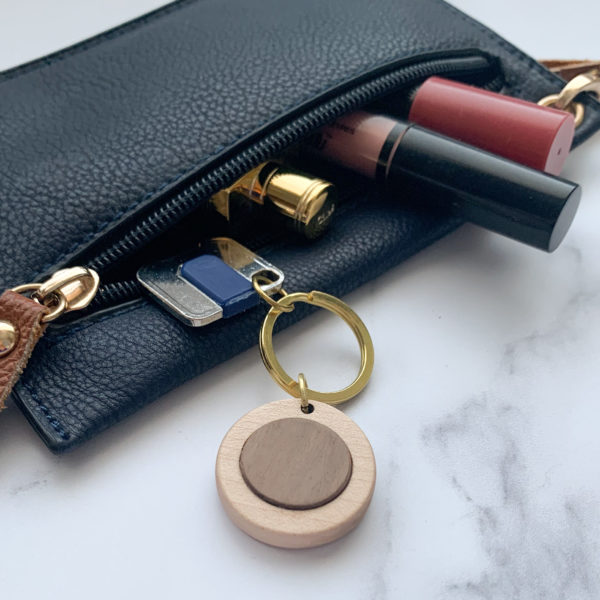 Pale white wood round key ring with walnut inlay, displayed with key in purse
