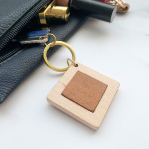 Pale white wood square key ring with mahogany inlay, displayed with key