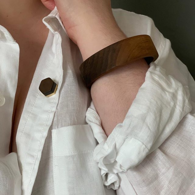 Vannucchi Jewellery model wears walnut wood and brass hex pin with a walnut bangle