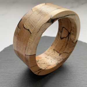 Shot from a side angle, Vannucchi Jewellery Rachael spalted beech bangle stood upright on slate