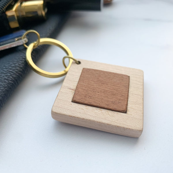 Pale white wood square key ring with mahogany inlay, displayed with key