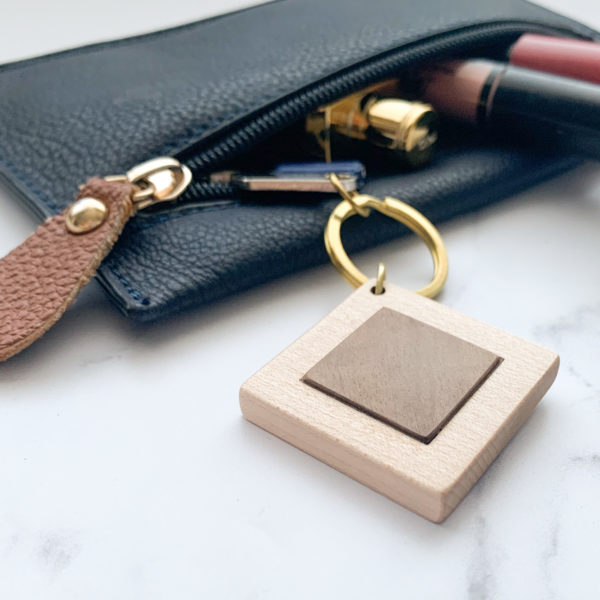 Pale white wood square key ring with brass metal inlay, displayed with key in purse