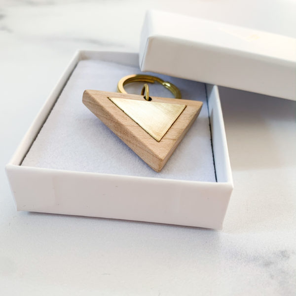 Pale white wood triangle key ring with brass metal inlay, displayed in Vannucchi Jewellery branded box