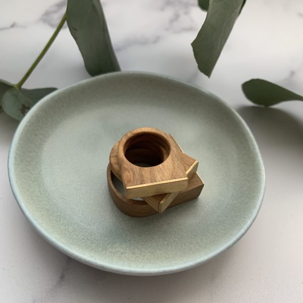 Aqua coloured dish holds three of Vannucchi Jewellery's Cally, olive wood and brass, square topped rings
