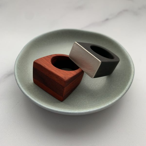 Vannucchi's Whitney ring, black ebony and silver displayed resting on top of Padauk, red wood ring