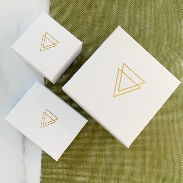 Three Vannucchi branded boxes of different shape and size. White with gold icon in centre