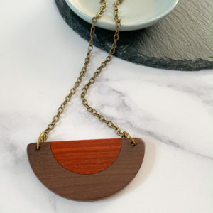Belle brown and red wood semi circular necklace displayed draped over aqua coloured dish