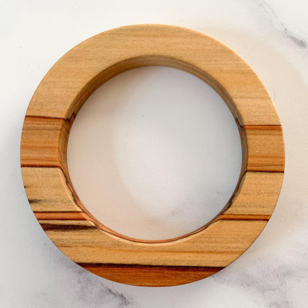 Birds eye view of red coloured stripes running through Sara parana pine wood bangle created by Vannucchi Jewellery