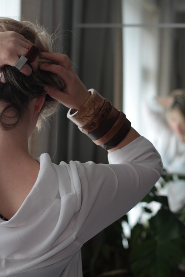 Model holds up hair and shows right arm full of wooden bangles