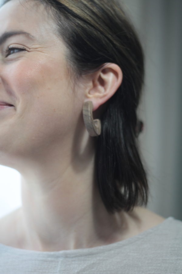 Model smiling whilst wearing Vannucchi Jewellery's walnut Claire Earrings