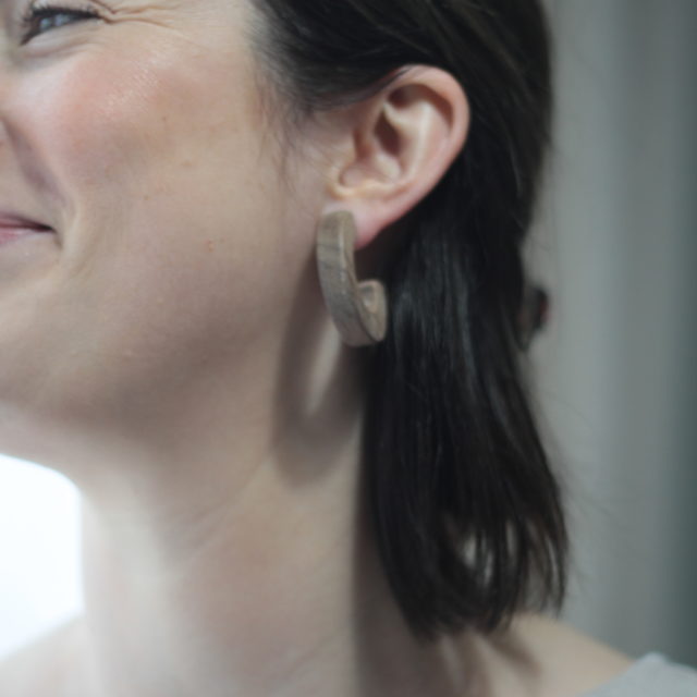 Model smiling whilst wearing Vannucchi Jewellery's walnut Claire Earrings