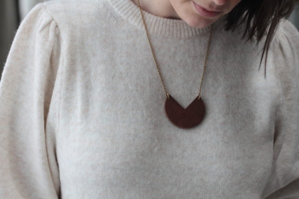 Vannucchi model looks down and show front facing shot of sector shaped Fiona wood laminate necklace