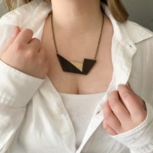 Vannucchi Jewellery model wears white shirt, she pulls aside to reveal Rose wood geometric necklace