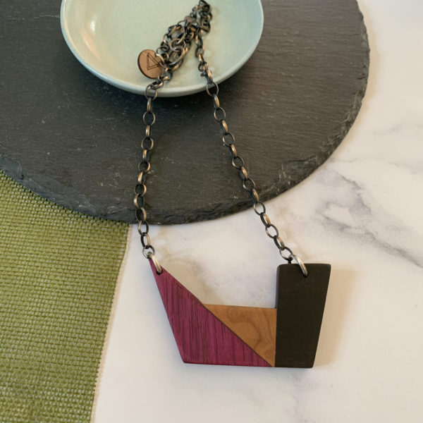 Vannucchi Jewellery Plum geometric necklace draped over aqua coloured dish
