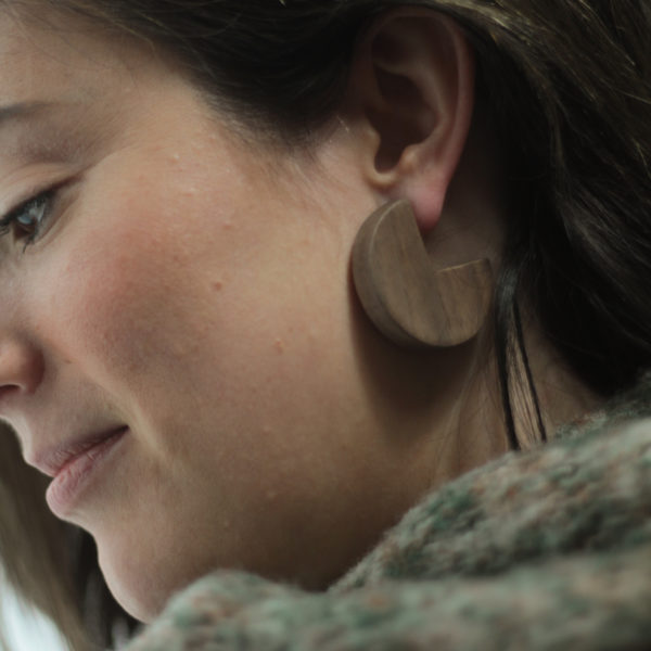 Vannucchi Model looks down whilst wearing Ellie walnut wood, sector shaped earrings