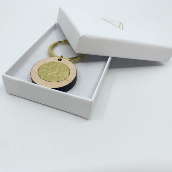 textured brass and wood key ring in branded packaging