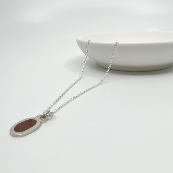 Collezione XXI Wood Pebble Necklace displayed on white background, laid over a white dish.
