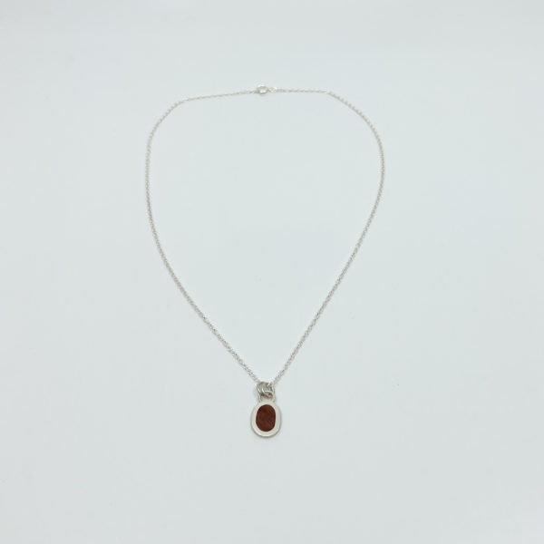 Collezione XXI Wood Pebble Necklace is displayed on white background. Long fine silver chain with pebble shaped pendant made from silver and light red wood.