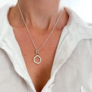 Model wears white shirt, open slightly to expose the Collezione XXI Stone Necklace. Fine silver chain with square wire, irregular geometric shaped pendant.