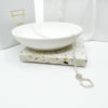 Collezione XXI Stone Necklace is displayed laid over a white dish, with white Vannucchi packaging in the background, showing gold logo.