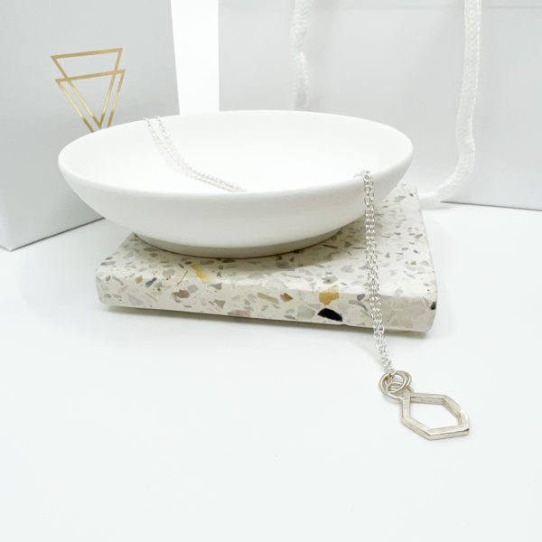 Collezione XXI Stone Necklace is displayed laid over a white dish, with white Vannucchi packaging in the background, showing gold logo.