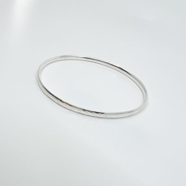 Highly polished collezione XXI hammered bangle displayed on white background