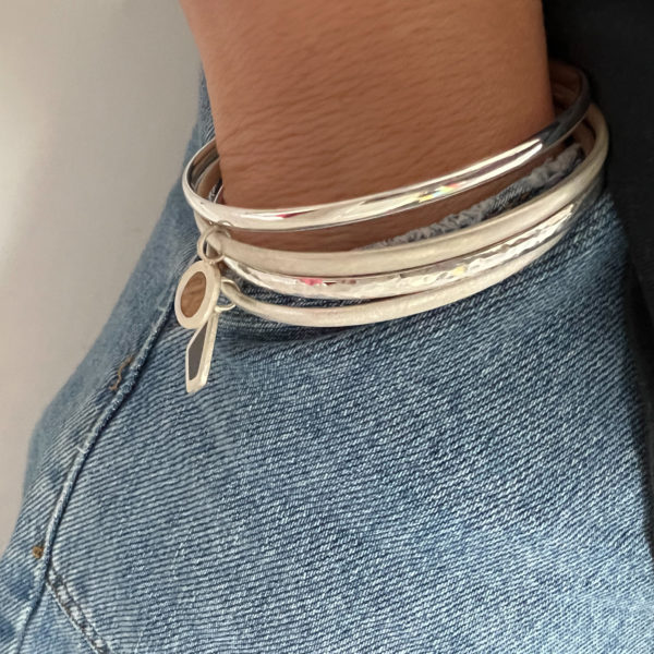 Model wears multiple Collezione XXI bangles with hand in jeans pocket.