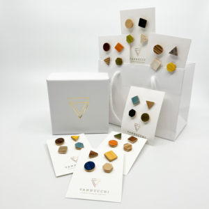 A selection of colourful wood pin sets. Sets of four geometric shaped pins displayed with white Vannucchi packaging on a white background.