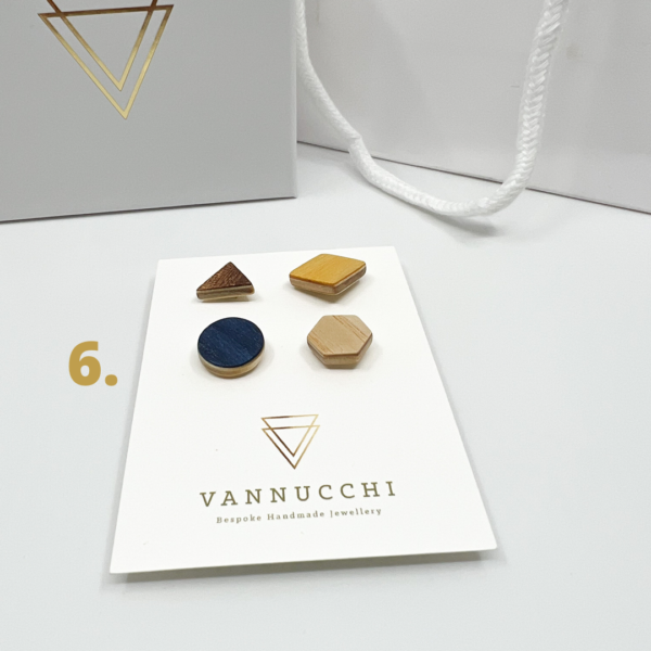 Mix and Match Veneer Pin Set six consists of four mixed geometric shaped wood pins. Coloured yellow, oak, navy blue and dark brown veneers. Displayed on white Vannucchi backing card.