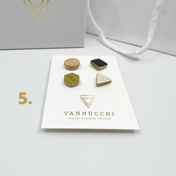 Mix and Match Veneer Pin Set five has four mixed geometric shaped wood pins, with black, white, olive green and light maple veneers. Displayed on white Vannucchi backing card.