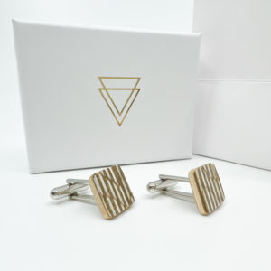Cufflinks displayed with white Vannucchi branded box on white back ground. Cufflinks are brown and white stripe veneer. Cut square with white metal cuff link attachment.