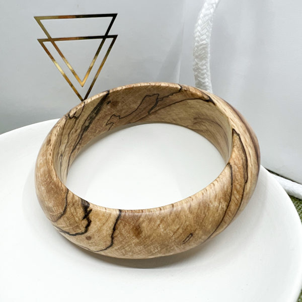 ginny spalted beech bangle displayed on white dish with branded box in background