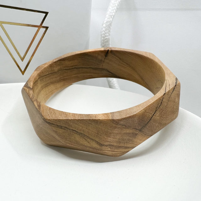 Florence multi angled Olive bangle displayed on white dish with branded box in background