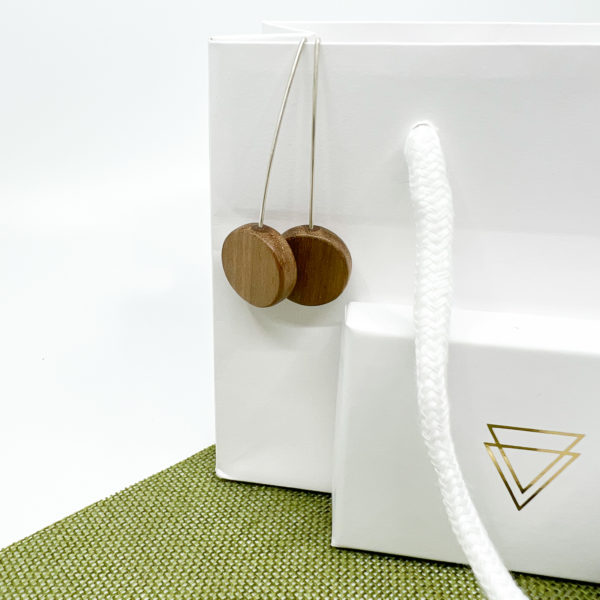 Walnut and silver Hanging earrings displayed on white gift bag with branded box on white and green background.