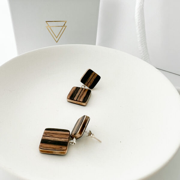 Collezione XXIII Banda Earrings displayed on white dish with branded box in background.