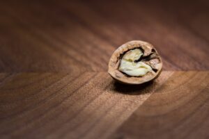 A halved walnut sat on a brown walnut wood back ground.